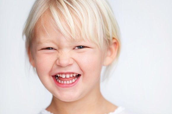 Barn som ler och visar sina mjölktänder