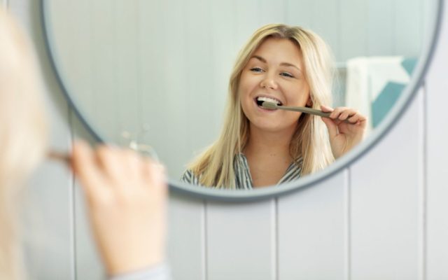 Girl brushing her teeth with Jordan Green Clean toothbrush. 