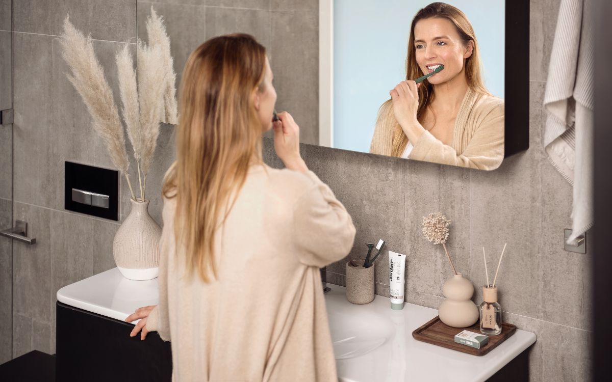 Person som står framför en spegel och borstar tänderna