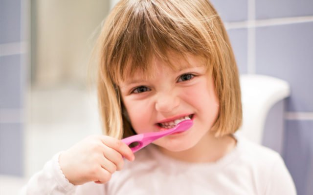 Child brushing her teeth with Jordan Kids toothbrush. 