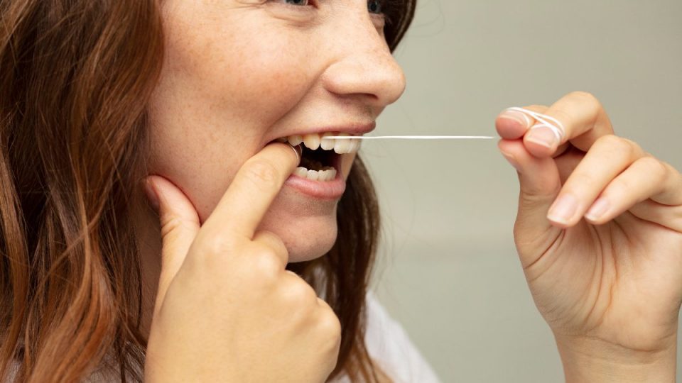 Person som gör rent mellan sina tänder med hjälp av tandtråd från Jordan