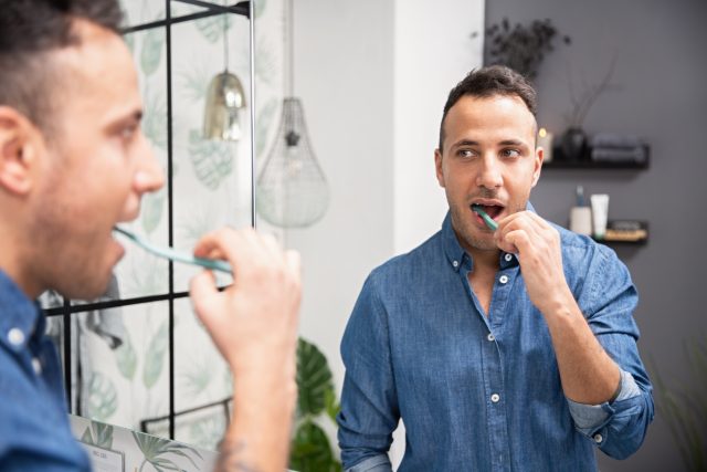 Man brushing his teeth with Jordan Green Clean toothbrush. 