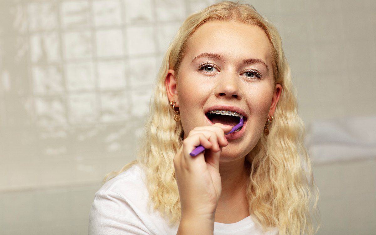 Ung person med tandställning som borstar tänderna