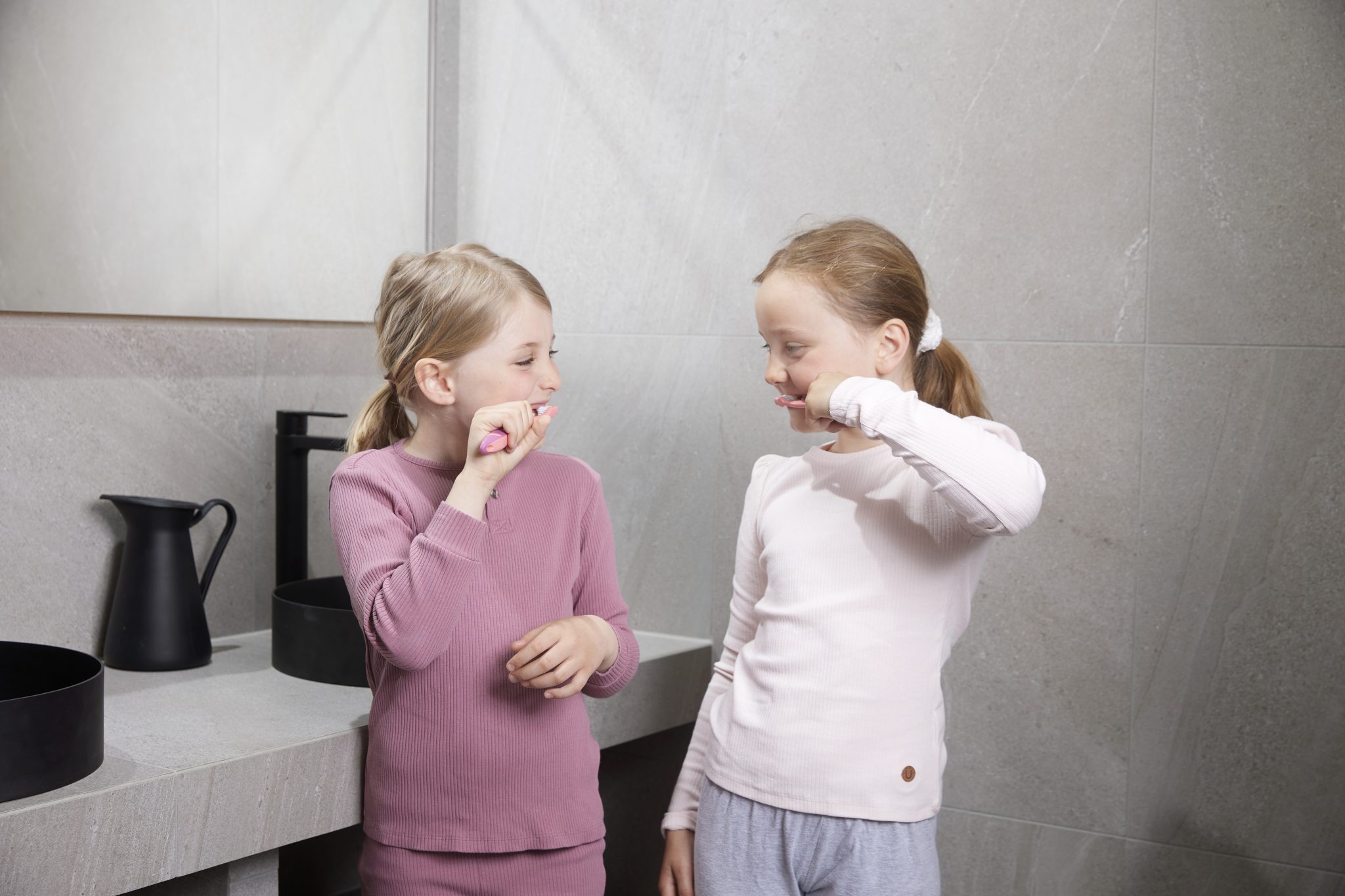 Två barn som borstar tänderna med Jordan barntandborstar som visar hur mycket tandkräm barn ska använda