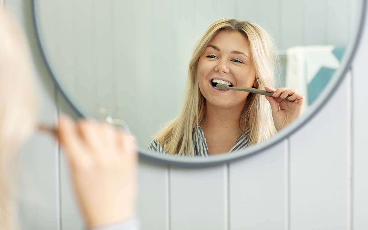 Kvinne pusser tennene med Jordan tannbørste.