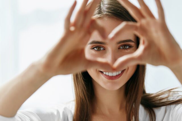 Donna bellissima mostra il simbolo del cuore con le mani