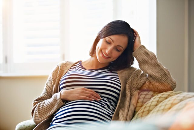 Donna incinta sorridente si tocca la pancia