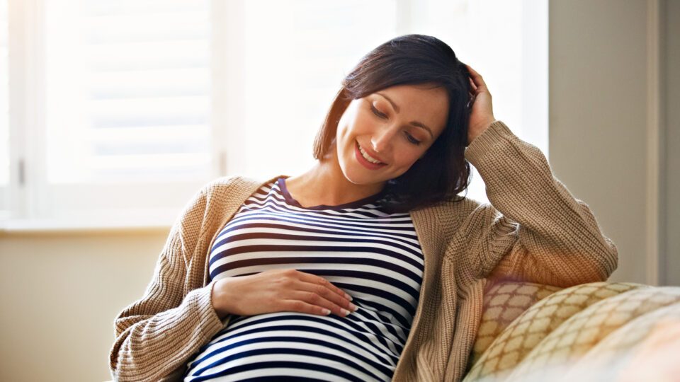 Donna incinta sorridente si tocca la pancia